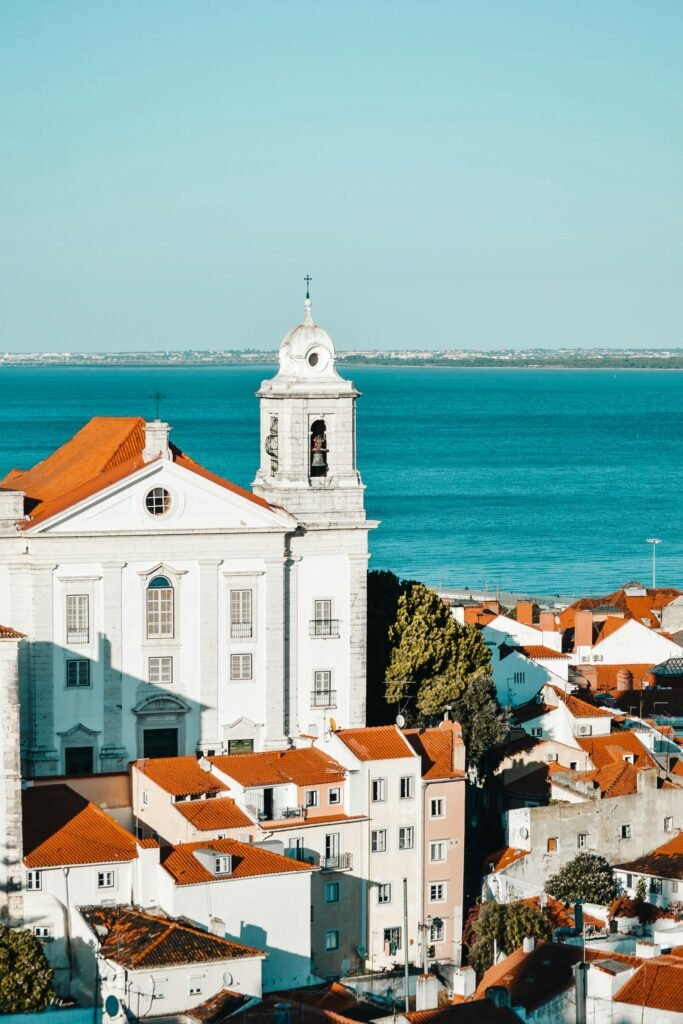 A picturesque view of Lisbon's Alfama district with traditional architecture overlooking the azure sea.